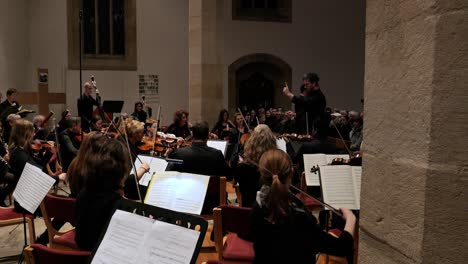 Static-handheld-slow-motion-shot-of-a-talented-orchestra-with-conductor,-violin-players-and-flute-players-during-a-concert-to-classical-music-by-mozart