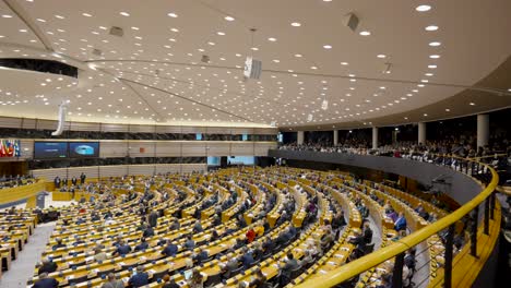 Audience-sitting-in-the-European-Parliament-tribune-during-the-plenary-session-in-Brussels,-Belgium---panning-shot