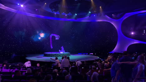 Men-and-Women-in-audience-looking-for-seats-before-watching-stage-show-on-a-cruise-ship-in-theater