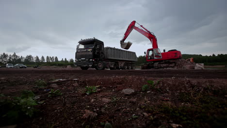 Bagger-Transportiert-Sand-Und-Stein-In-Den-Transporter-Auf-Der-Baustelle