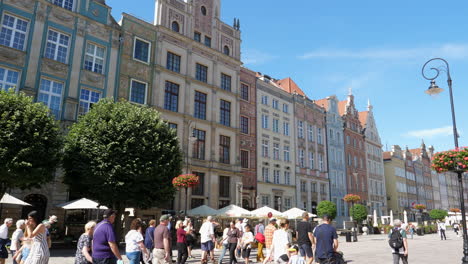 Coloridas-Casas-Adosadas-Del-Centro-Histórico-De-La-Ciudad-Vieja-De-Gdansk,-Inclinadas-Hacia-Abajo-Revelando-Turistas-En-La-Calle