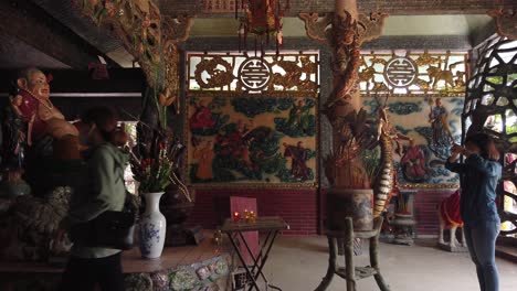 Interior-with-worshippers-of-Phu-Chau-pagoda-or-floating-temple,-an-old-Chinese-style-Buddhist-place-of-worship-in-the-middle-of-the-Phuam-Thuat-river-in-Go-Vap-district-of-Ho-Chi-Minh-City,-Vietnam