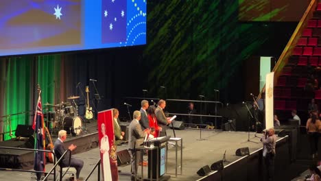 Representantes-Elegidos-Que-Reciben-Su-Certificado-De-Ciudadanía-Del-Alcalde-Adrian-Schrinner-En-El-Escenario,-Ceremonia-De-Gran-Tamaño-De-Brisbane-Debido-A-Una-Pandemia-En-El-Centro-De-Convenciones-Y-Exposiciones-De-Brisbane