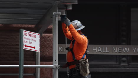 Trabajador-De-La-Construcción-Usando-Un-Martillo-En-Andamios-En-La-Ciudad-De-Nueva-York