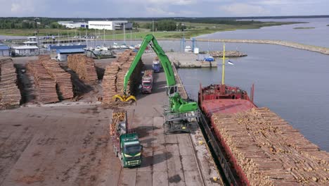 Kran-Lädt-Holzstämme-Vom-LKW-Auf-Frachtschiff-Im-Hafen-Voller-Holzstapel,-Totale,-Statisch