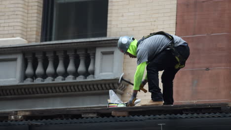 Trabajador-De-La-Construcción-De-Pie-Usando-Un-Martillo-En-Clavos-Largos-En-El-Sitio-En-Nueva-York