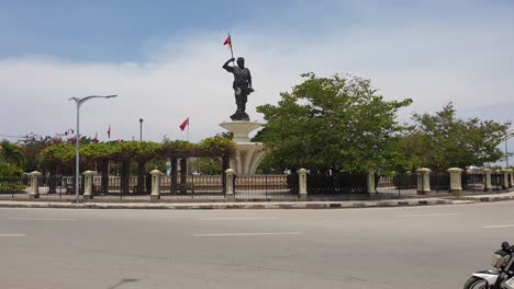 Estatua-Histórica-De-Nicolau-Dos-Reis-Lobato,-Héroe-Nacional-De-Timor-Oriental,-Y-Tráfico-En-La-Ciudad-Capital-Dili,-Timor-Leste,-Sudeste-De-Asia