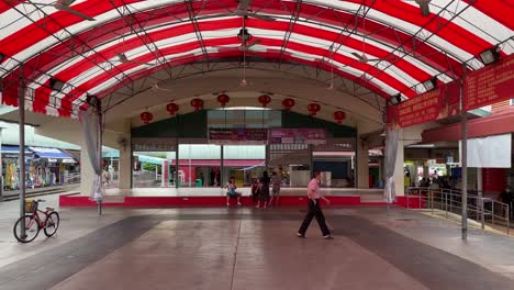 La-Gente-Descansa-En-La-Zona-Común,-Y-Un-Hombre-Camina-Hacia-El-Centro-De-Vendedores-Ambulantes-En-El-Barrio-De-La-Ciudad-De-Chong-Pang,-Singapur