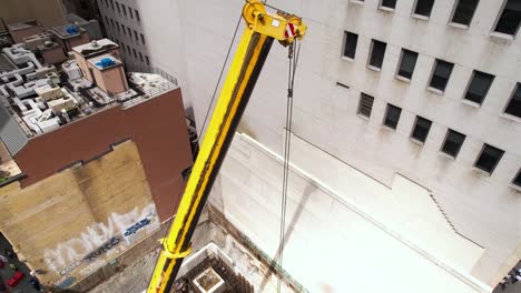 Aerial-view-around-a-crane-at-a-construction-site-in-middle-of-buildings-in-Midtown,-NYC---circling,-drone-shot