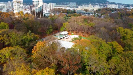 Drohne-Fliegt-Vorwärts-Und-Enthüllt-Open-Air-Freizeitzentrum-Inmitten-Eines-Großen-Parks-In-Der-Stadt-Varna,-Bulgarien