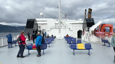 Toma-Estática-De-Personas-Esperando-Y-Haciendo-Turismo-En-La-Cubierta-De-Un-Ferry-Mientras-Cruza-En-Un-Día-Nublado-Pero-Soleado