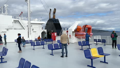 Medium-panning-shot-of-passenger-on-a-ferry-smoking-or-enjoying-the-sights-while-sailing-across-the-ocean-under-a-cloudy-but-sunny-sky