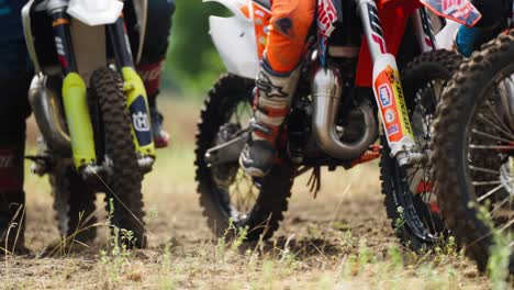 Eine-Gruppe-Von-Motocross-rennfahrern-Macht-Sich-Bereit-Für-Ein-Wettkampfrennen,-Das-Auf-Motorrädern-Sitzt-Und-Auf-Den-Start-Wartet---Schwenken-Im-Niedrigen-Winkel