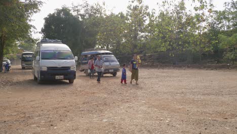 Pequeña-Familia-Asiática-Caminando-Por-Caminos-Rurales-Sucios-Mientras-Pasan-Viejos-Autobuses