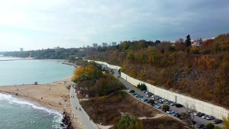 Toma-Aérea-De-La-Costa,-El-Mar-Y-Las-Colinas-En-La-Ciudad-Búlgara-De-Varna,-Playa,-Cielo-Despejado-Y-Tráfico-Turístico