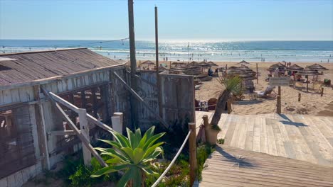 Beautiful-sunny-day-at-the-beach-in-Lisbon-Portugal,-little-beach-restaurant-by-the-ocean,-fun-holiday-summer-vacation,-4K-shot