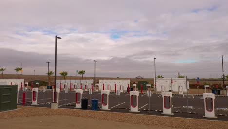 Estación-De-Sobrealimentación-Tesla-Con-Muchas-Estaciones-De-Carga,-Todas-Con-Energía-Solar,-Sobrevuelo-Bajo-De-Drones-4k