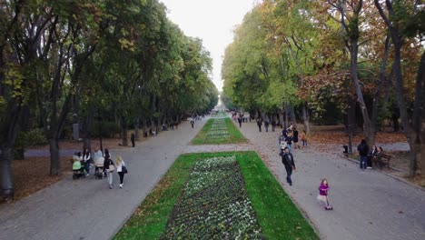 People-walking-through-Sea-Garden-in-Varna-and-enjoying-the-evening,-Bulgaria,-drone-shot