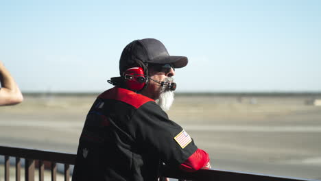 Miembro-Del-Personal-De-Carreras-De-Autos-Equipado-Con-Auriculares-De-Comunicación-Viendo-La-Carrera-En-Curso