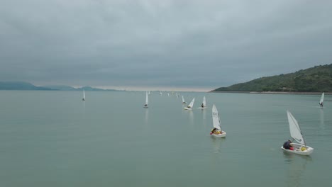 Zahlreiche-Segeljollen,-Die-An-Einem-Bewölkten-Tag-Segelunterricht-In-Der-Bucht-Durchführen