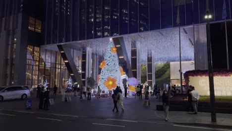 Gente-China-Caminando-Por-La-Entrada-Del-Hotel-Con-Una-Enorme-Instalación-De-árboles-De-Navidad-Por-La-Noche