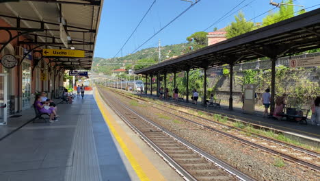 Train-in-distance-arriving-at-railway-station-and-waiting-passengers-in-Italy-Santa-Margherita