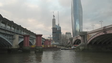 Desarrollo-De-Astilleros-Bancarios-En-Construcción-En-Londres-Con-Un-Edificio-Blackfriars,-Puente-Blackfriars-Y-Estación-De-Tren,-Remolcador-Tirando-De-Contenedores-De-Envío-Por-El-Támesis