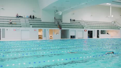 Nadadores-Entrenando-En-Piscina-Cubierta-En-Natatorio-Moderno