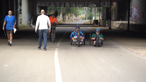 Men-ride-on-adaptive-bicycle-with-hand-cycle-in-Yarkon-Park-in-Tel-Aviv,-Israel