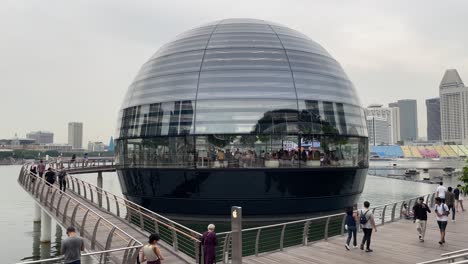 La-Gente-Camina-Y-Visita-La-Futurista-Tienda-Minorista-Insignia-De-Apple-Frente-Al-Mar-En-Marina-Bay,-Singapur