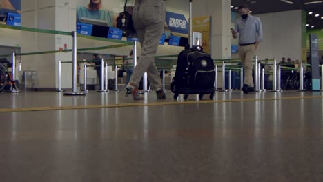 Toma-A-Nivel-Del-Suelo-De-Pasajeros-Con-Carritos-De-Equipaje-Pasando-La-Entrega-De-Equipaje-En-El-Aeropuerto