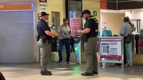 Autorisierte-Einheitliche-Fahrkarteninspektoren-Warten-Vor-Dem-Umzäunten-Bahnhof,-Fangen-Schwarzfahrer-zugreisende-Ein-Und-Stellen-Sicher,-Dass-Die-Passagiere-Eine-Gültige-Fahrkarte-In-Fortitude-Valley,-Brisbane,-Haben