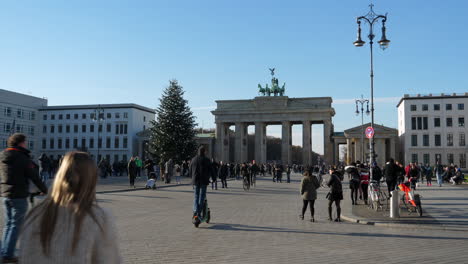 Menschen,-Die-Auf-Dem-Pariser-Platz,-Nahe-Dem-Brandenburger-Tor,-In-Berlin,-Deutschland,-Spazieren-Gehen-Und-Auf-Stehenden-Elektrorollern-Fahren