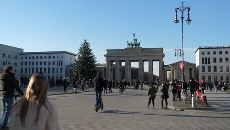 Gente-Caminando-Y-Montando-Scooters-Eléctricos-De-Pie-En-Pariser-Platz,-Cerca-De-La-Puerta-De-Brandenburgo,-En-Berlín,-Alemania