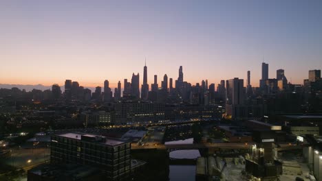 Aerial-view-over-the-Chicago-River,-towards-skyscrapers-in-the-Near-north-side-of-the-city,-colorful-dawn-in-Illinois,-USA