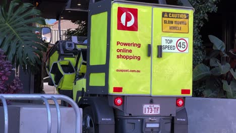 Primer-Plano-De-Un-Estacionamiento-De-Vehículos-De-Correos-De-Australia-Frente-Al-Apartamento,-Entregando-Paquetes-A-La-Puerta