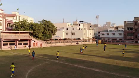 Aerial-drone-shot-of-teenager-player-playing-football-in-the-ground-of-Pakistan