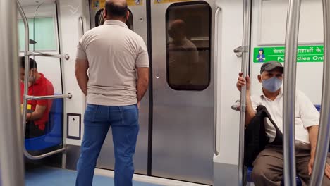 passenger-traveling-in-metro-waiting-to-deboard-at-metro-station-from-back-video-is-taken-at-new-delhi-metro-station-new-delhi-india-on-Apr-10-2022