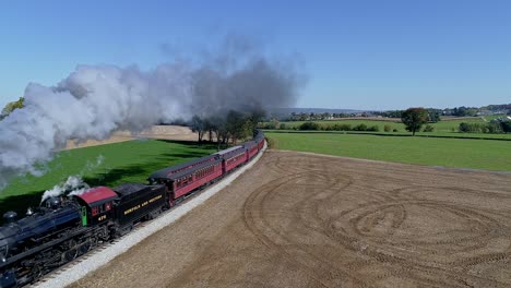 Drone-Arriba-Y-A-La-Vista-Lateral-De-Un-Tren-De-Pasajeros-De-Vapor-Que-Redondea-Una-Curva-En-Un-Día-Soleado