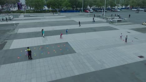 Niños-Aprendiendo-Patinaje-Sobre-Ruedas-En-El-Patio-De-Recreo-En-El-Centro-De-Guangzhou-Por-La-Noche