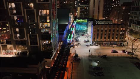 Aerial-view-tracking-the-CTA-Holiday-train,-night-in-South-Loop,-Chicago,-USA