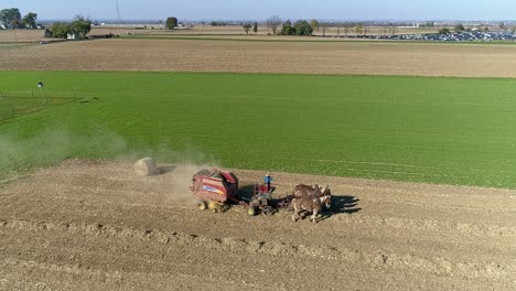 Aerial-View-of-an-Amish-Man-and-Woman-Harvesting-Corn-Stalks-and-Bailing-in-Squares-with-Horse-Drawn-Equipment-on-a-Sunny-Fall-Day