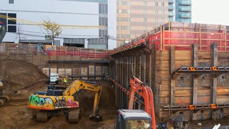 Panoramablick-Auf-Die-Baugrube-Für-Ein-Hochhaus-Mit-Baggerarbeiten-Umgeben-Von-Einer-Baustellenkulisse