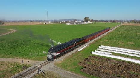 Vista-De-Drones-De-Un-Tren-De-Pasajeros-De-Vapor-Que-Sopla-Mucho-Humo-Y-Vapor-Parado-En-Un-Día-Soleado-De-Otoño