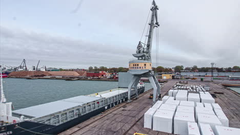 Crane-loading-shipping-containers-on-a-cargo-ferry---day-to-night-time-lapse