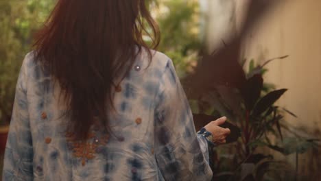 Slow-motion-of-a-brunette-Indian-woman-walking-away-and-looking-at-some-plants,-in-the-historical-streets-of-Fontainhas,-India