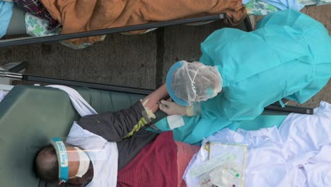 Un-Trabajador-De-La-Salud-Toma-Una-Muestra-De-Sangre-De-Un-Paciente-Chino-Enfermo-Con-Síntomas-De-Covid-19-Acostado-En-La-Cama-Fuera-De-Un-Hospital-Abarrotado-Mientras-El-Sistema-Médico-Colapsa-Con-Las-Hospitalizaciones