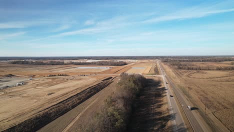 Aerial-approach-of-sprawling-new-construction-adjacent-to-cars-travelling-on-highway