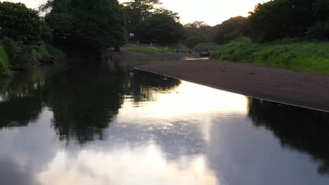 Río-Tarcoles-Con-Botes-Turísticos-Cargando-Pasajeros-Turísticos,-Carro-Aéreo-En-Tiro