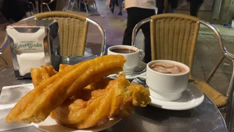 Nahaufnahme-Einiger-Porras-Und-Churros-Mit-Heißer-Schokolade-An-Einem-Tisch-In-Der-Straße-Der-Alten-Bar-Von-San-Gines,-Madrid